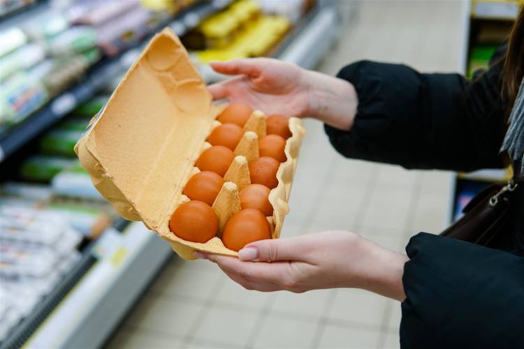 Kobieta wybierająca opakowanie jajek podczas zakupów w sklepie spożywczym